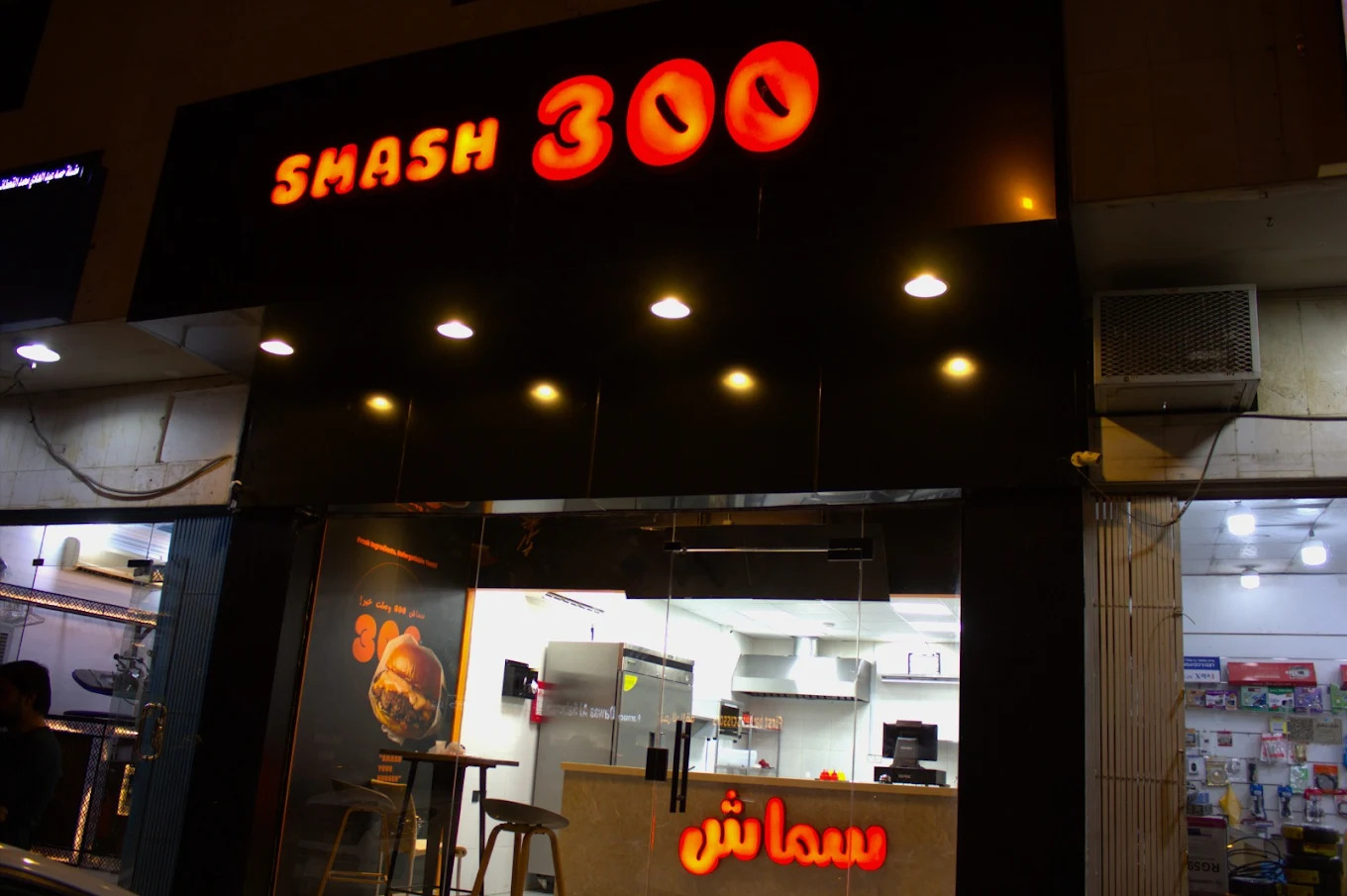 واجهة مطعم سماش 300 المضيئة باللون البرتقالي ليلاً في الرياض